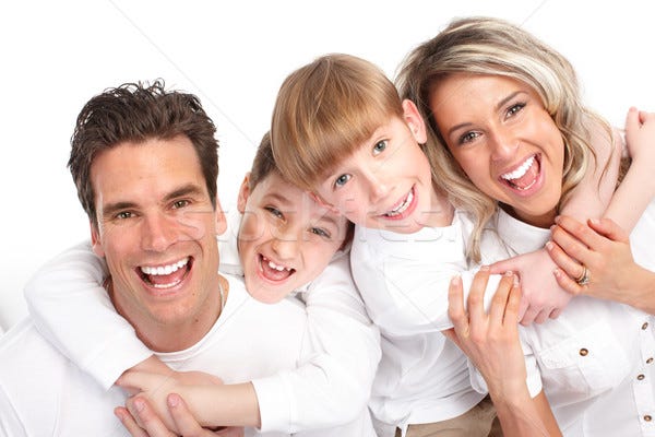 A stock photograph of a man, a woman and two boys in white shirts on a white background, piled together with their arms around each other, all four laughing open-mouthed at the camera.
